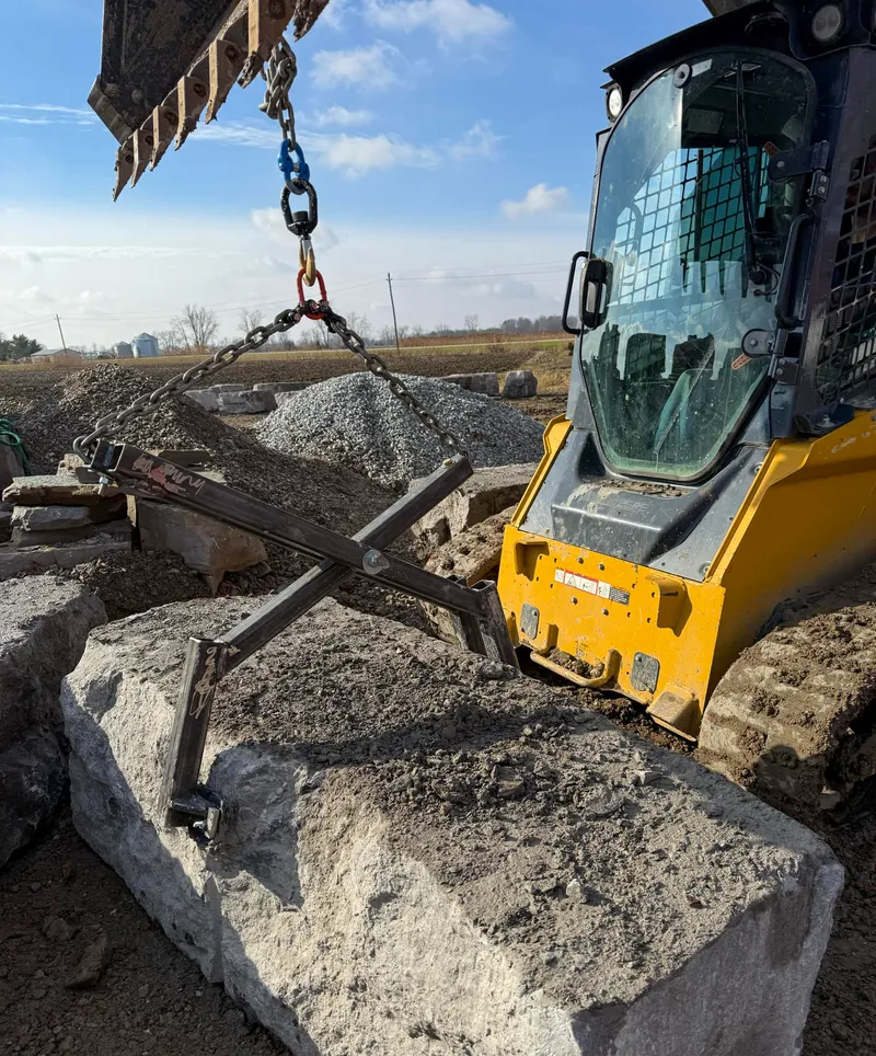 Excavator moving large stones at construction site