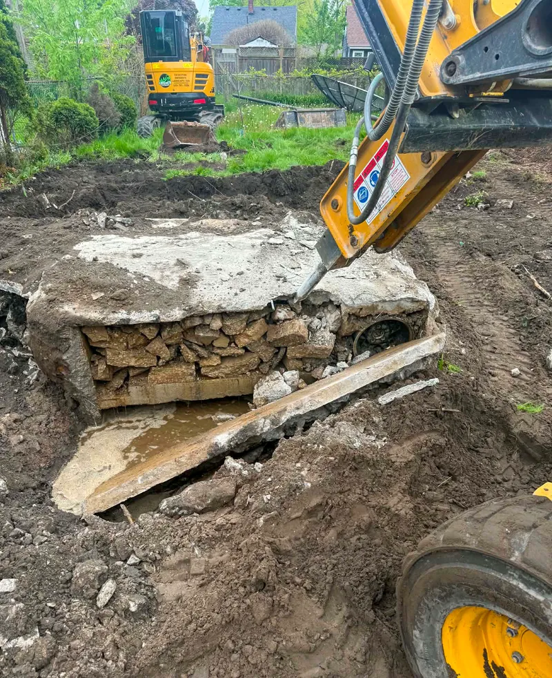 Hydraulic breaker demolishing a buried concrete structure during excavation