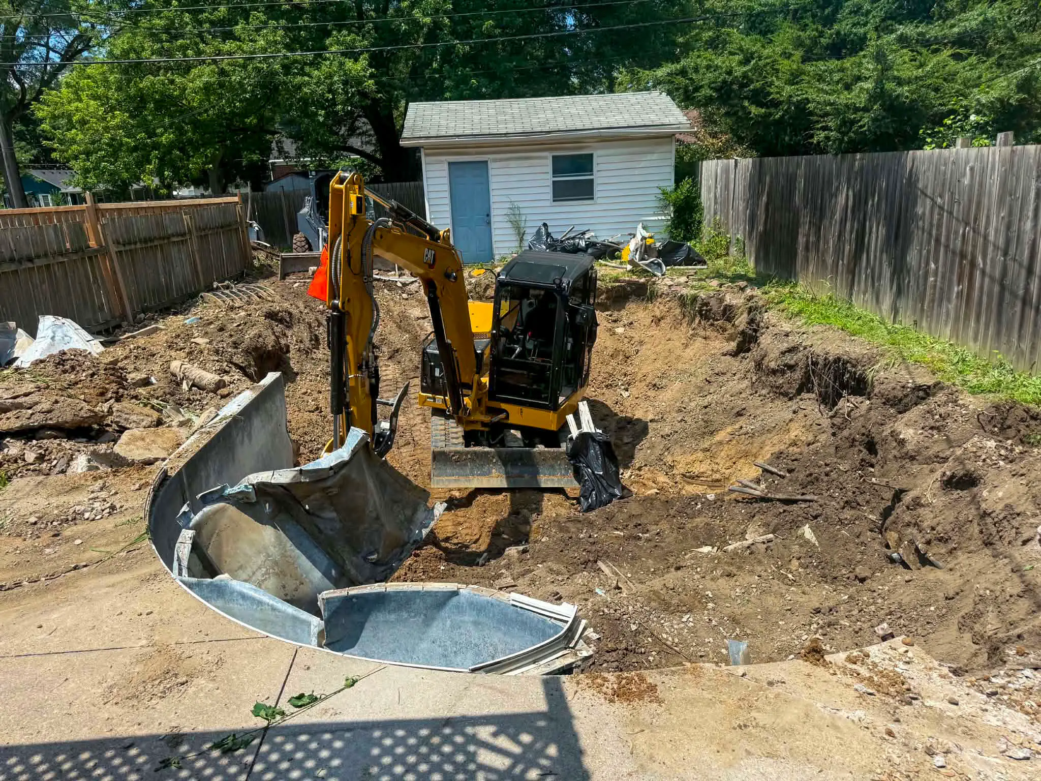 Mini excavator folding pool walls down during complete pool removal
