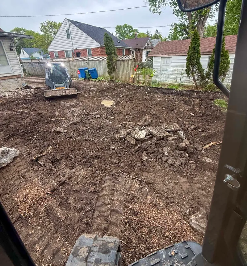 Skid steer clearing and grading a residential lot